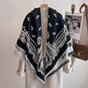 Nahaufnahme eines schwarz-weißen Paisley-Schals mit Fransen auf einem Wollmantel
