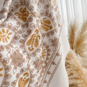 Close-up of golden embroidery on white cashmere scarf with fringe details