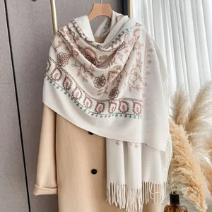 Detail of floral embroidery and fringe on a cream cashmere-like winter pashmina shawl