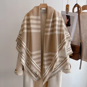 Gros plan d'une écharpe à carreaux kaki classique avec franges sur un manteau beige