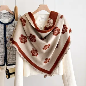 Detail of knit beige shawl with dark red rose pattern and soft frayed fringe edges