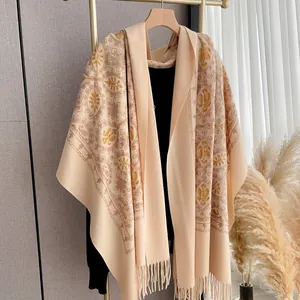 Detailed close-up of vintage floral embroidery and fringe on beige cashmere-like shawl