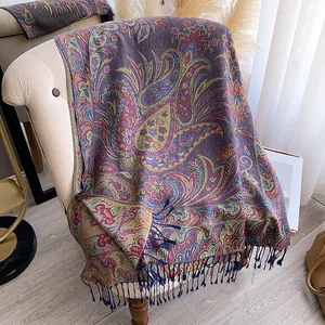 Detail of intricate Paisley pattern scarf with long fringe on a light armchair