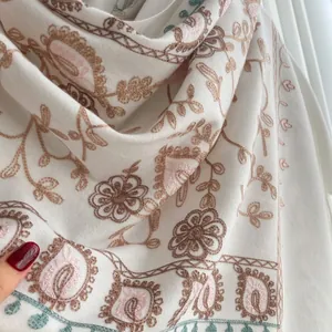 Detail of floral embroidery and paisley patterns on a soft white pashmina with tassels