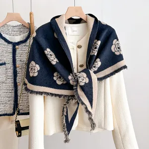 Detail of navy knit shawl with beige camellia patterns and delicate fringe trim