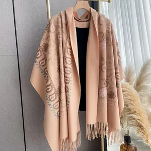 Detail of bohemian floral embroidery and tassels on soft apricot cashmere-feel shawl