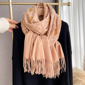 Close-up of golden floral embroidery and soft fringe on this light pink cashmere shawl