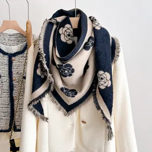 Detail of camellia jacquard scarf with fringe edges draped over a white blazer