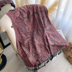 Detail van Boheemse sjaal met paisley-motief en franjes op een stoel in zacht licht