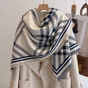Détail d'une écharpe pied-de-poule bleu marine et crème avec franges sur un manteau