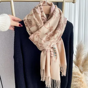 Detail of floral embroidery on a soft beige cashmere-feel scarf with elegant fringes