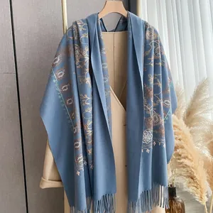 Detail view of grey-blue cashmere scarf with floral embroidery and long fringes