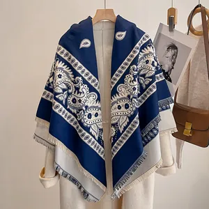 Detail eines Paisley-Schals mit Fransen, kombiniert mit einem cremefarbenen Wollmantel
