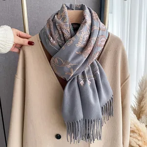 Detailed view of floral embroidery and fringe on a soft dark grey pashmina scarf