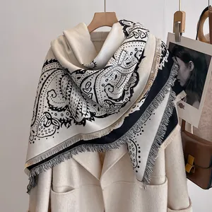 Texture détaillée du châle paisley noir et blanc avec franges sur un manteau beige
