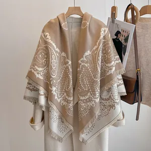 Détail d'un châle pashmina beige avec motifs paisley blancs et bordures à franges