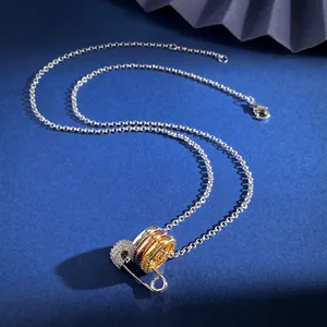 Detail von dreifarbigen Ringen an Sicherheitsnadel-Anhänger mit Kristallen und Kugelkette