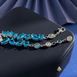Detailaufnahme der silbernen Halskette mit blauen Kristallen und Verschluss auf Geschenkbox