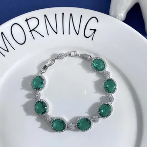 Detailed view of silver tennis bracelet with emerald oval stones and zircon floral accents