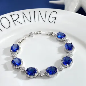 Close-up of sparkling oval blue gemstone bracelet with micro-pave crystals on white plate