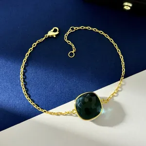 Elegant gold chain bracelet featuring a cushion-cut green crystal centerpiece