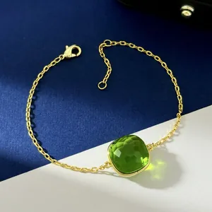 Detail of gold chain bracelet featuring a square green crystal pendant and lobster clasp