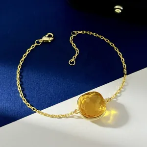 Detailed shot of a gold chain bracelet with a square yellow crystal and lobster clasp