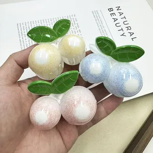 Detalle de pinzas para el cabello de bayas coloridas con textura mate y hojas verdes