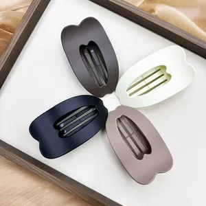 Close-up of four matte heart-shaped hair claws in coffee, cream, black, and taupe tones
