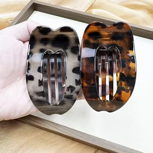 Detail view of large leopard print heart-shaped claw clips in grey and amber acetate