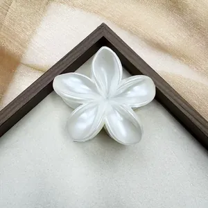 Gros plan détaillé d'une pince à cheveux fleur de frangipanier blanc nacré à fini brillant