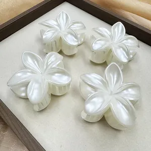Vue détaillée de quatre pinces à cheveux frangipane blanches nacrées sur satin doré