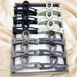 Detailed view of large matte bow hair claws in neutral colors on a silk background