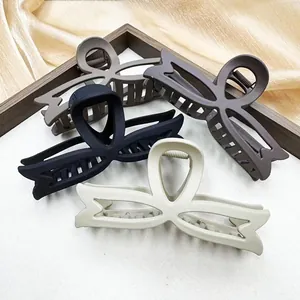 Matte bow-shaped hair claw clips set in neutral colors with elegant silk backdrop