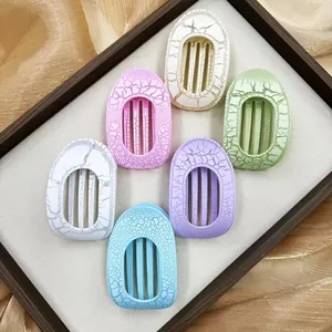 Flat oval hair claws with crackle glaze finish in six colors on a wooden tray