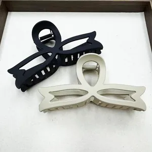 Detailed view of matte bow hair claws in black and beige tones on a minimalist tray