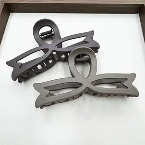 Detail of matte hollow bow hair claws in dark coffee and grey-brown colors with metal spring