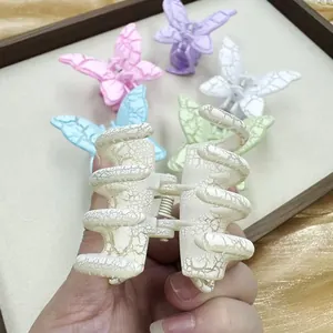 Détails d'une pince à cheveux papillon pastel avec une texture craquelée et fini mat doux