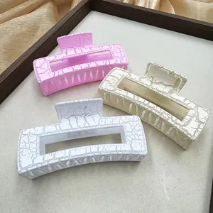 Détail de trois grandes pinces à cheveux à texture marbrée en rose, beige et blanc