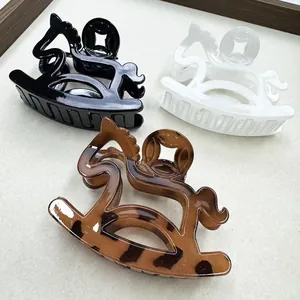 Three minimalist horse-shaped hair claws in black, white, and tortoiseshell patterns