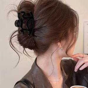 Close-up of a large black animal-shaped hair claw clip styling a low bun on brown hair