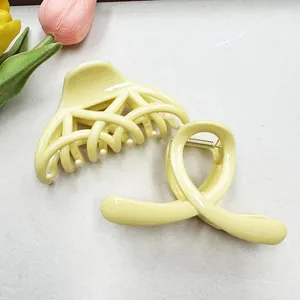 Close-up of yellow claw hair clips with hollow weave and infinity spiral designs