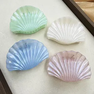 Detail view of shell-shaped hair claws in pastel colors with shimmery pearlescent finish