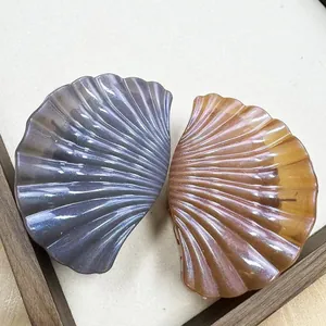 Close-up of elegant seashell-shaped hair claws with pearlescent finish and stripe texture