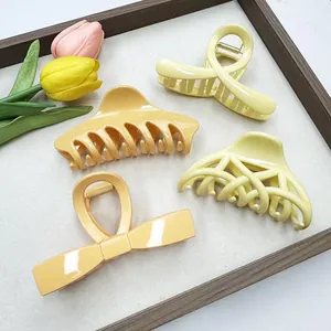 Set of four hollow shark hair clips in warm yellow tones on a wooden tray with tulips