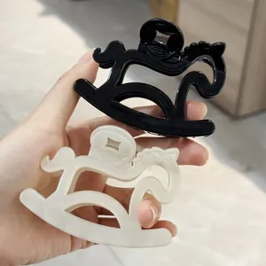 Detail of horse-shaped hair clips in black and cream pearlescent acetate finish