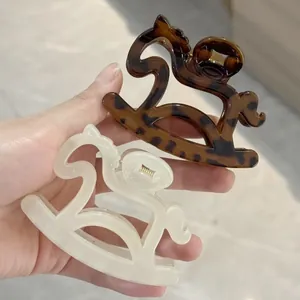 Close-up of tortoise shell and cream acetate horse-shaped hair claws for elegant hairstyling