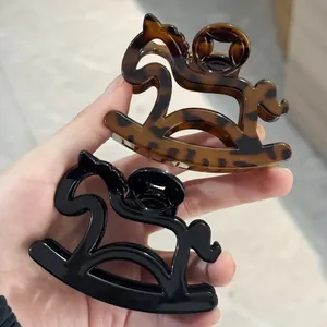 Close-up of tortoise shell and black rocking horse claw clips with polished finish