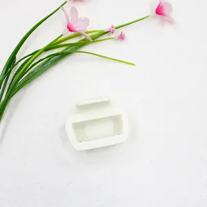Detail van een kleine witte rechthoekige matte haarklem met bloemdecoratie