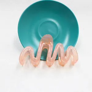 Dettaglio della molletta per capelli a onde in acrilico rosa-arancio traslucido
